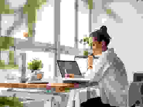 women sitting in her home office on her laptop smiling
